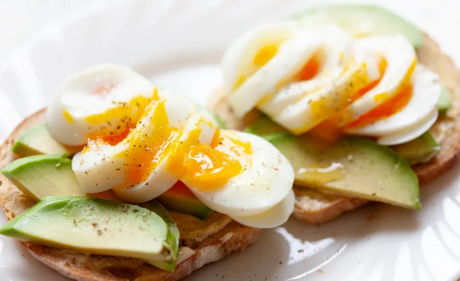 dish with sourdough breaed, boiled eggs and avocado slices