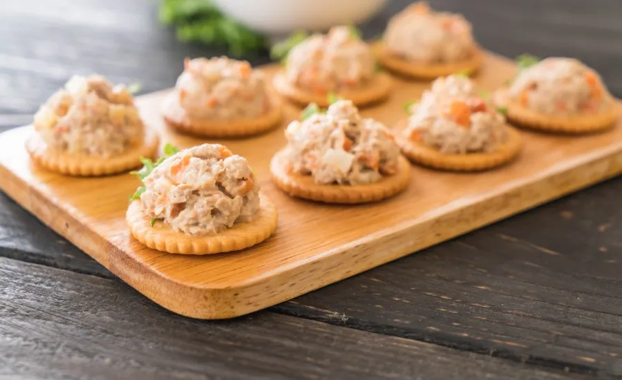 a wood plate with crackers and tuna