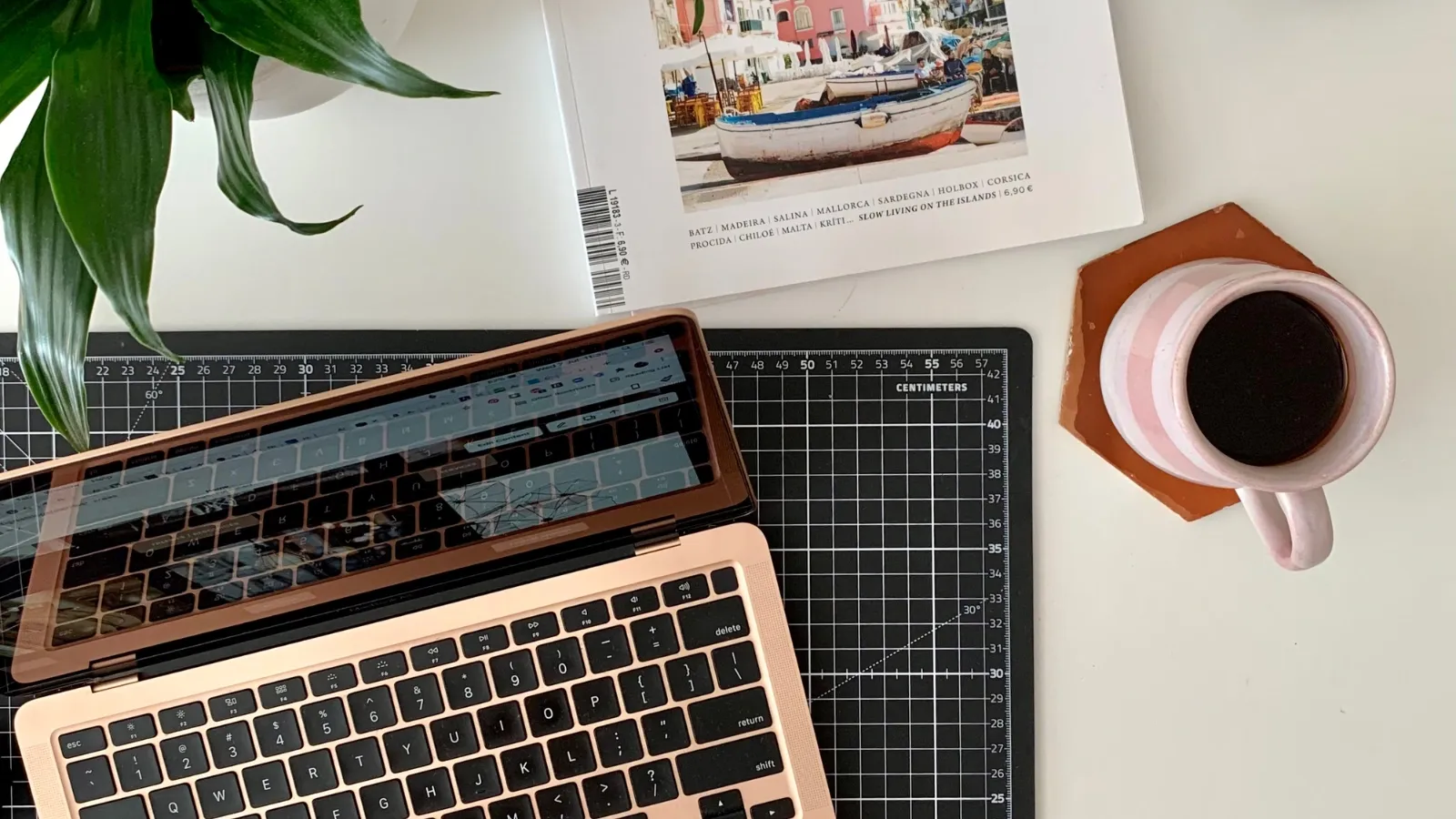 desk with a laptop, a cup of coffee and a book