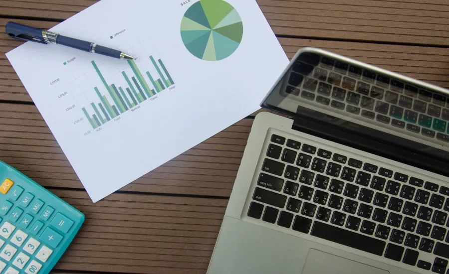 a desk with a laptop, a chart document and a calculator
