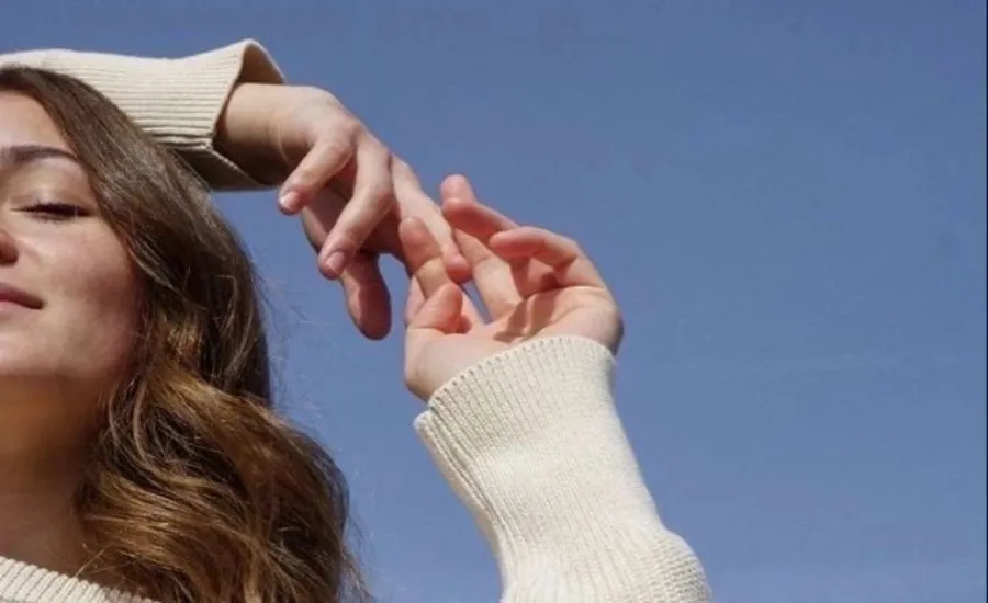 woman's face holding her hands above her head
