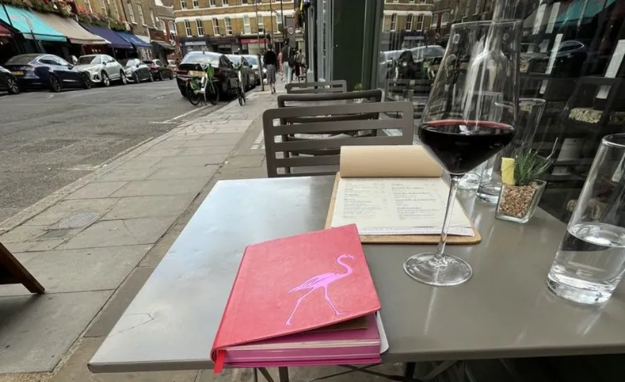 a table with a diary and a glass of red wine in a parisian bistrot